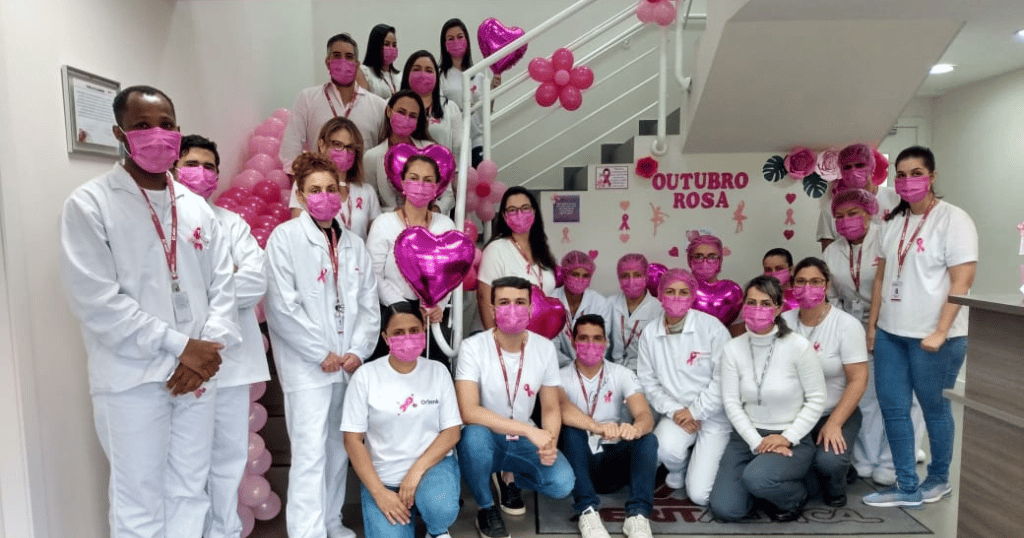 Images of members of the Merit team in Brazil wearing pinks face masks, posing for a breast cancer awareness photo